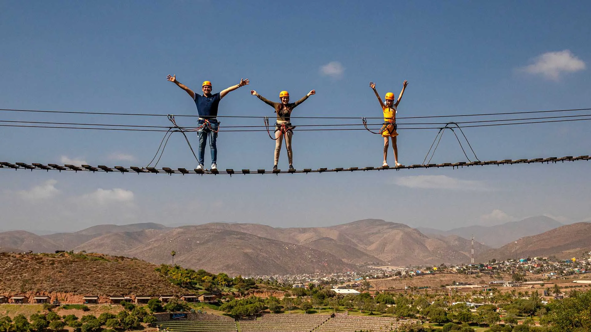 Visitors standing on a high suspension bridge above the Las Cañadas valley