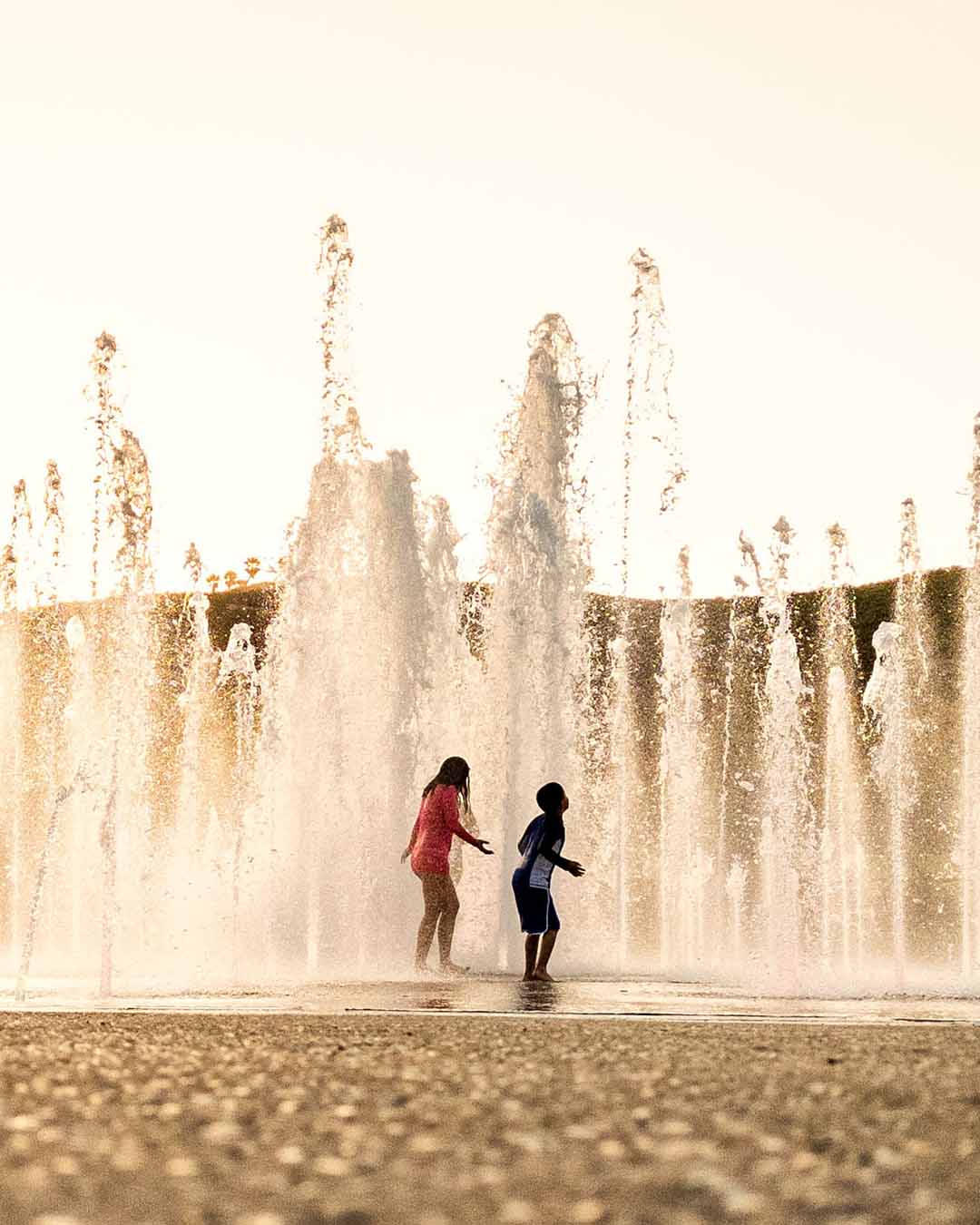 Children running through tall water jets at the Las Cañadas interactive splash pad